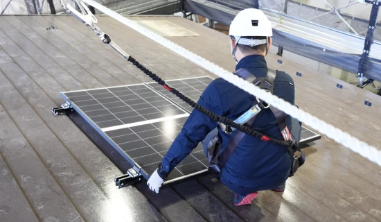 屋根の上で太陽光パネルを施工するスタッフ